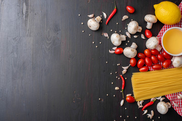 Fototapeta na wymiar Spaghetti ingredients on black wooden desk, top view.