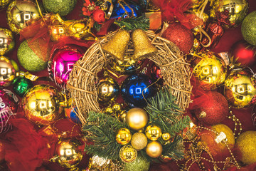 Christmas wreath with golden bell and colorful balls in the background.