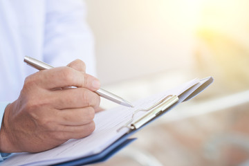 Close-up image of doctor taking notes in medical history of patient