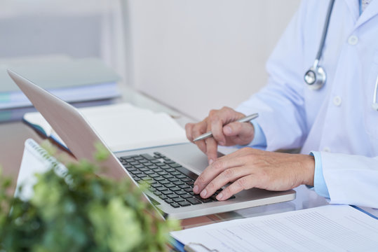 Cropped image of general practitioner working on laptop at her table