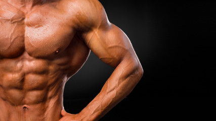 Fototapeta premium Young handsome sportsman bodybuilder weightlifter with an ideal body, after coaching poses in front of the camera, abdominal muscles, biceps triceps chest.