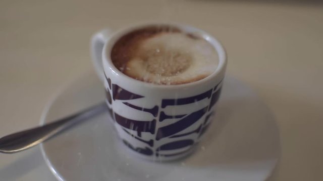 Brown sugar falling in a cup of espresso coffee. Zucchero di canna cade nella tazzina con il caff&radic;&reg; macchiato.