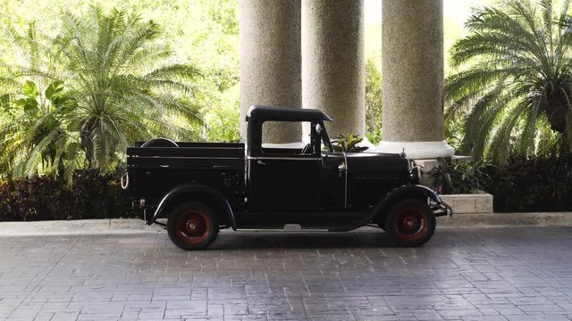 Old pickup truck parked in front of a hotel lobby