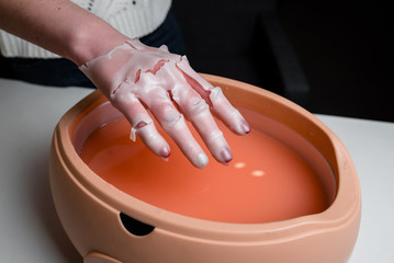 Process paraffin treatment of female hands in beauty salon
