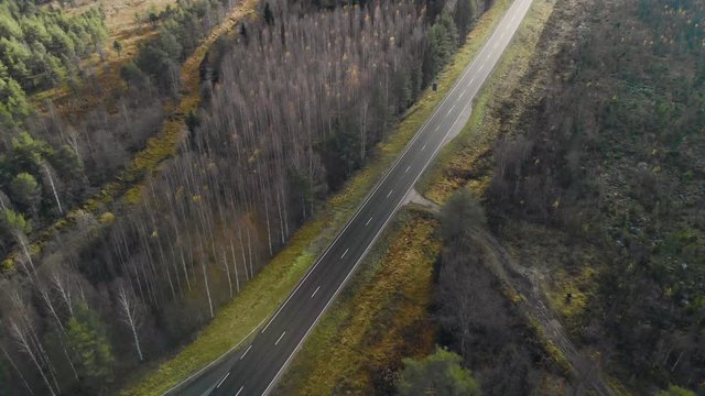 Aerial, tilt down, drone shot, flying towards a road and  leafless autumn forest, on a cloudy fall day, in Juuka, Pohjois-Karjala, Finland