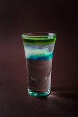 Clouds Alcoholic shot glass with absent, sambuca, tequila, blue curacao on elegant dark brown background