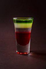 Alcoholic shot glass with grenadine, absent on elegant dark brown background