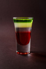 Alcoholic shot glass with grenadine, absent on elegant dark brown background