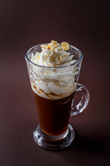 Glass of frappucino with whipped cream and almonds shaving on elegant dark brown background