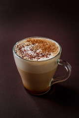Glass of coffee with chocolate topping on elegant dark brown background