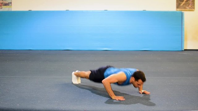 a guy doing a special kind of push up
in a top/side/front view still shot
inside a gymnastics gym