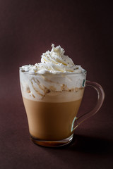 Glass of coffee with whipped cream on elegant dark brown background