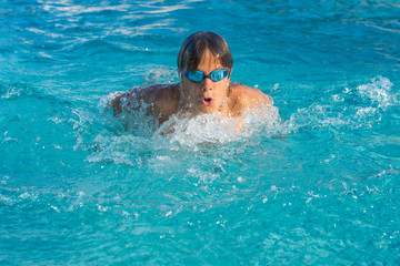 Close up action shot of teenage boy, young athlete swimming butterfly stroke. Sport, recreation, lifestyle concept.