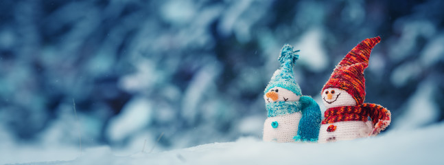 little knitted snowmans on soft snow on blue background