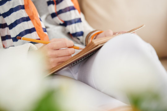 Close-up image of woman writing and drawing in planner or sketchbook