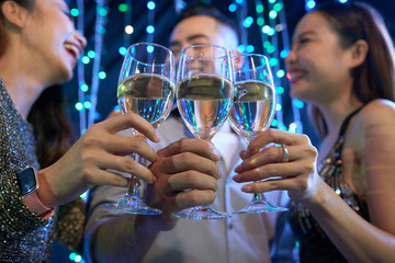 Young people clinking glasses of champagne at night party