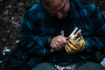 Close up of man carving branch with knife in nature