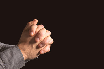 Hands of religious man praying on black background
