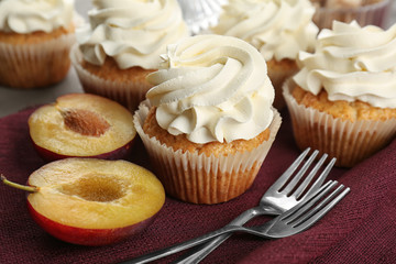 Sweet cupcakes and cut plum on table, closeup