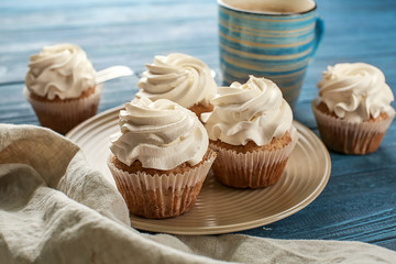 Plate with tasty cupcakes on wooden table