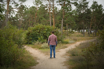 Young man standing at crossroads. Concept of choice