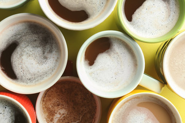 Many cups with tasty aromatic coffee on color background, top view