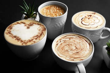 Cups with tasty aromatic coffee on black background