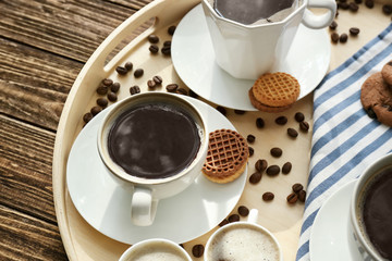 Cups with tasty aromatic coffee and cookies on tray