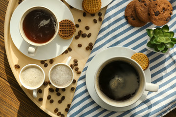 Tray with cups of tasty aromatic coffee on wooden table, top view