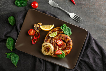 Plate with delicious roasted sausage and vegetables on table