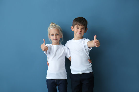 Boy and girl in t-shirts showing thumb-ups gesture on color background