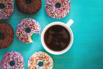 Delicious glazed donuts and cup of coffee on turquoise blue surface