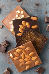 Handmade chocolate bars with nuts and coffee beans on a grey background