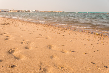 Footprints in the sand. Beautiful sandy tropical beach with sea waves.