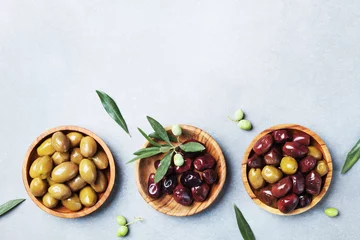 Outdoor kussens Set from olives in wooden bowls decorated with fresh olive tree branch top view. © juliasudnitskaya