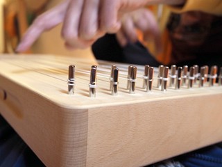 Sound healing therapy instrument Monochord, close up, with man hand playing on it.