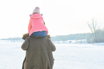 Vater trägt Tochter Huckepack im Winter