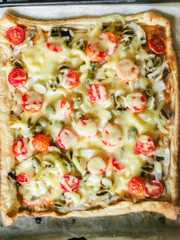 Cook preparing pizza. Closeup pizza with grated cheese, olives, tomatoes.