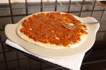 Spreading sauce over the pizza base