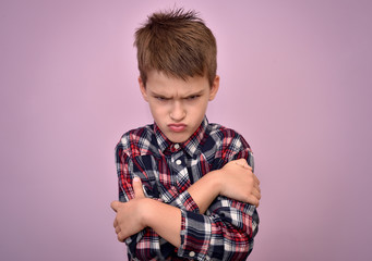 Angry and pouting cute young boy with crossed arms