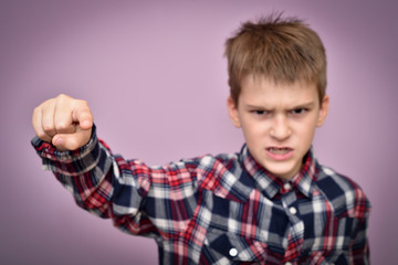 Angry and furious young boy pointing his index finger at camera. Focus on the index finger.