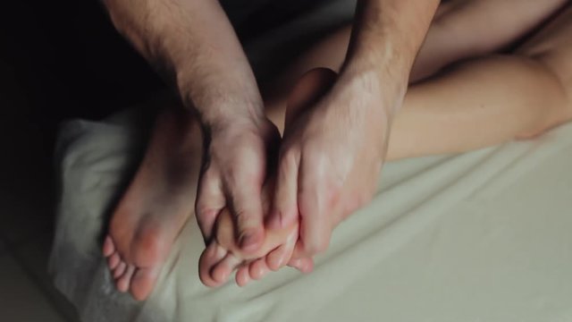 Young woman having feet massage in beauty spa salon. Close-up woman's legs and masseur's hands