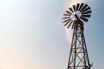 A Windmill silhouette with bright and blue sky. Beautiful american countryside icon.