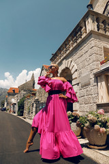 woman with blond hair in luxurious pink dress, having summer vacation in Europe