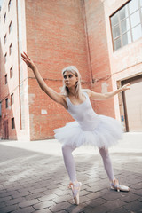 beautiful elegant young ballerina in white tutu dancing on street