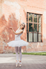 attractive smiling young ballerina dancing on urban street