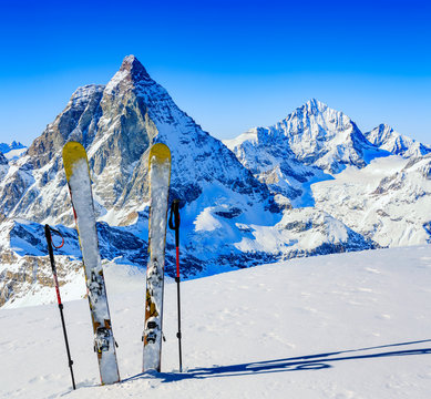 Ski in winter season, mountains and ski touring backcountry equipments on the top of snowy mountains in sunny day with Matterhorn in background, Zermatt in Swiss Alps.