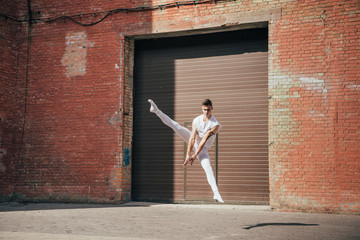 young ballet dancer dancing in jump on urban street