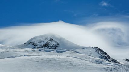 White winter mountains covered with snow in blue cloudy sky. Alps. Austria. Pitztaler Gletscher