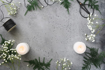 Christmas and New Year frame with plants and white burning candles on a grey background. Flat lay, top view, place for text.